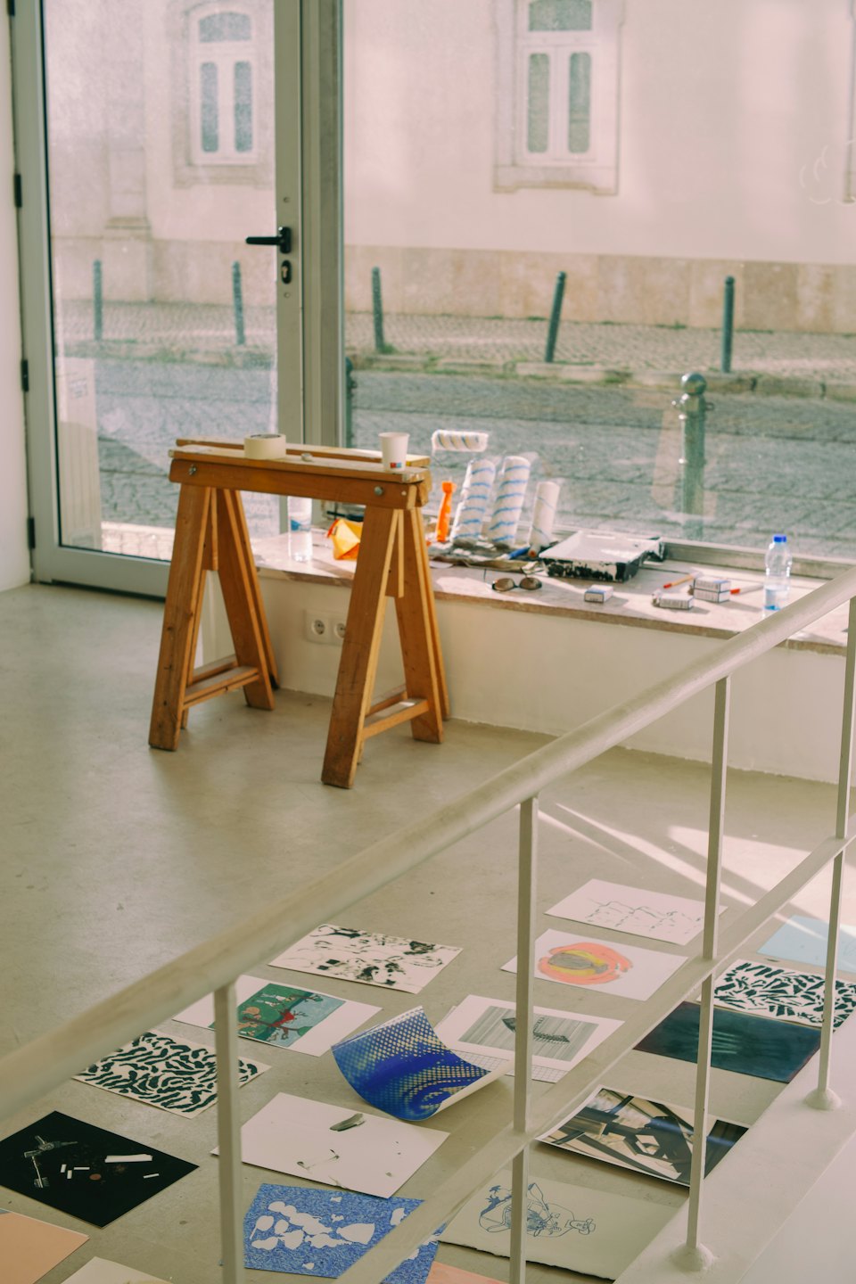 Studio d'arte con materiali sul pavimento di cemento e vista dalla finestra.