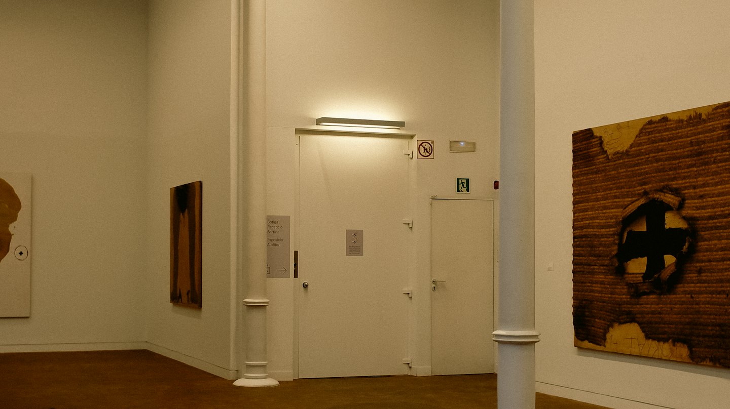 Tre dipinti astratti esposti sulle pareti bianche di una galleria.