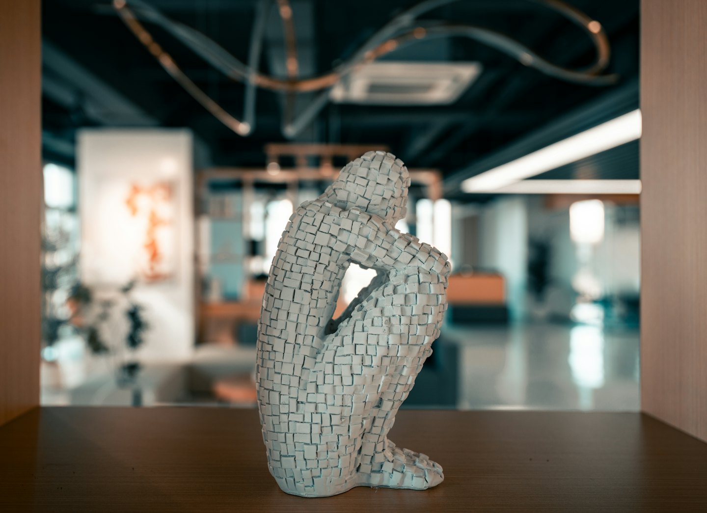 Scultura moderna bianca di una figura accovacciata su una scrivania di legno.